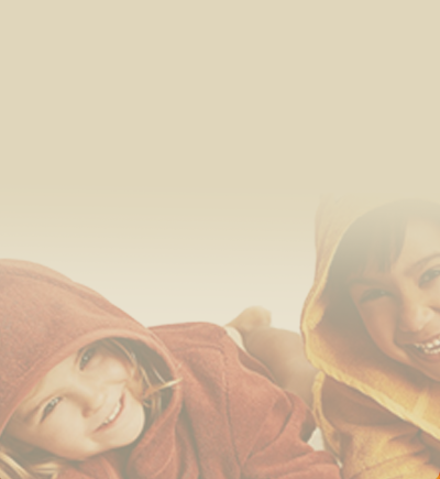 Zwei fröhliche Kinder in farbigen Bademänteln mit Kapuze